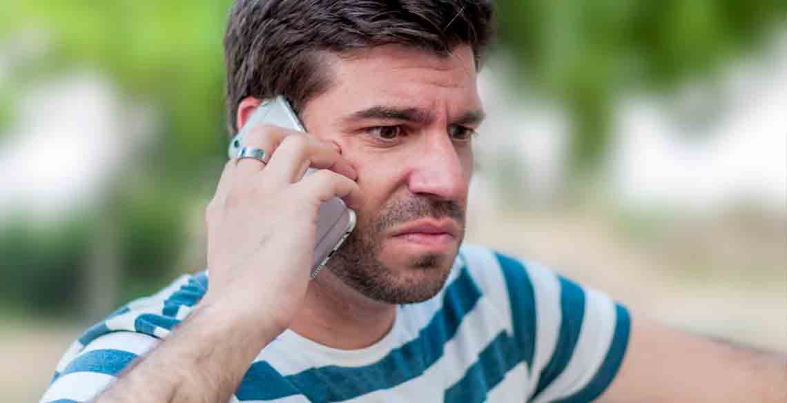 Un hombre atiende la llamada de un número desconocido con gesto de extrañeza